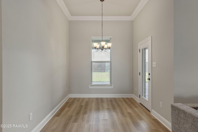unfurnished dining area with light wood-style floors, ornamental molding, baseboards, and a chandelier