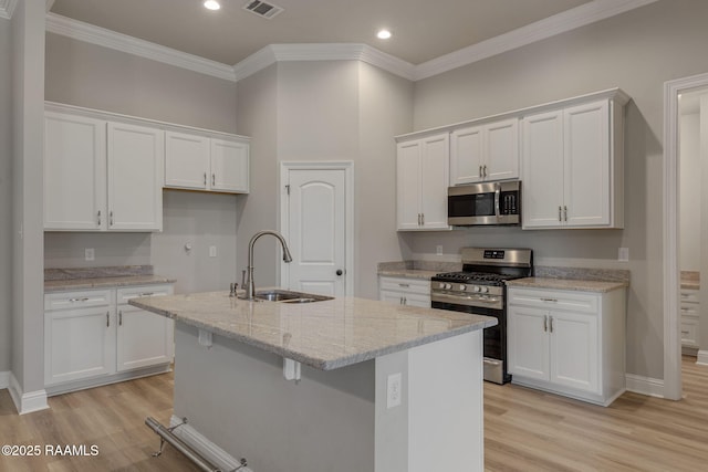 kitchen with a sink, light wood finished floors, appliances with stainless steel finishes, and white cabinets