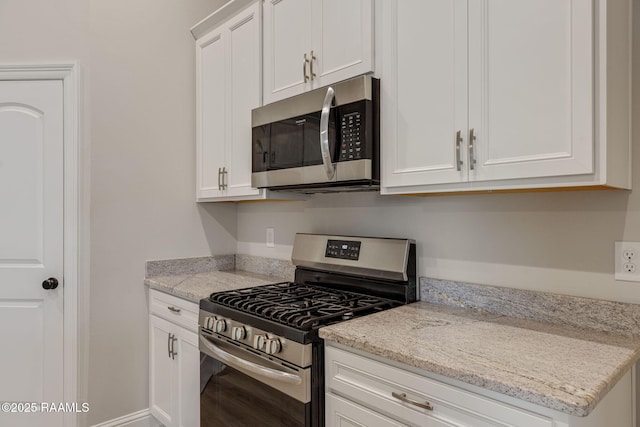 kitchen featuring light stone counters, stainless steel appliances, and white cabinetry