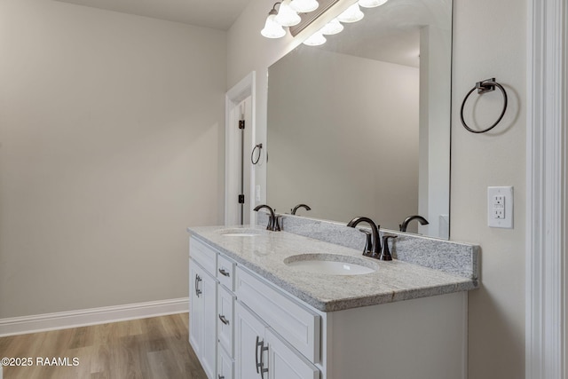bathroom with double vanity, a sink, baseboards, and wood finished floors