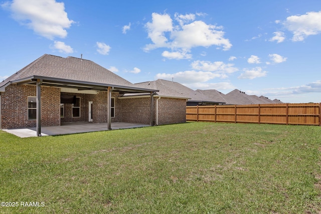 back of house featuring brick siding, a fenced backyard, a yard, and a patio