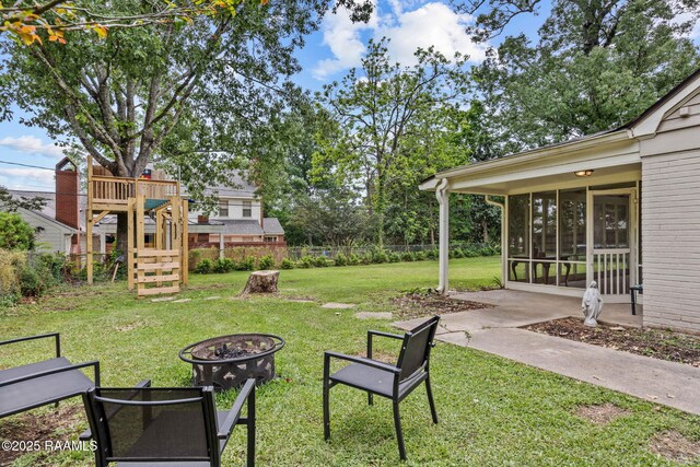 view of yard featuring fence, a fire pit, and a sunroom