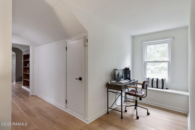 office space featuring vaulted ceiling, baseboards, and light wood-style floors