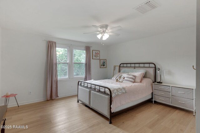 bedroom featuring light wood-type flooring, visible vents, a ceiling fan, and baseboards