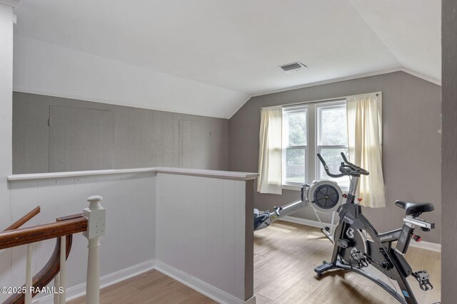 workout room with lofted ceiling, visible vents, and wood finished floors