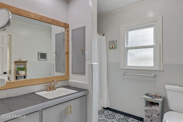 bathroom with tile walls, wainscoting, vanity, and toilet