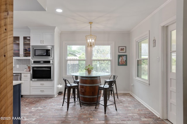 dining space with a chandelier, brick floor, a wealth of natural light, and baseboards