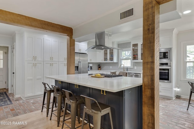 kitchen featuring brick floor, visible vents, appliances with stainless steel finishes, and exhaust hood