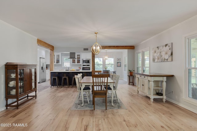 dining area with light wood-style floors, crown molding, baseboards, and a notable chandelier
