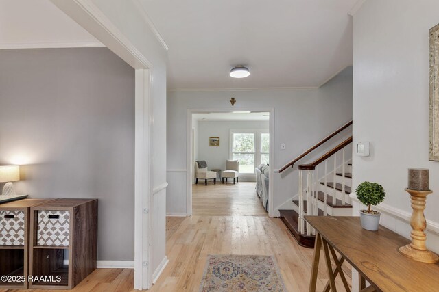 entrance foyer with baseboards, crown molding, stairs, and light wood finished floors