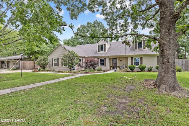 cape cod-style house with a shingled roof, a front lawn, and fence