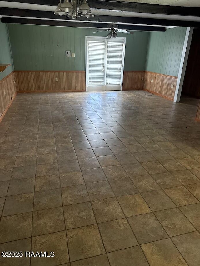 empty room with wooden walls, a chandelier, and wainscoting