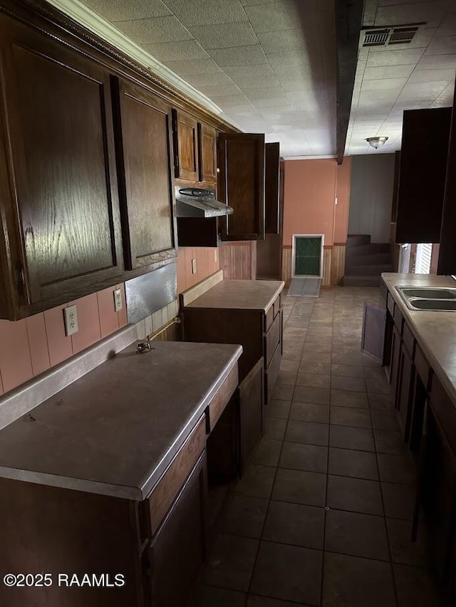 kitchen with visible vents, dark brown cabinets, dark tile patterned flooring, a sink, and extractor fan