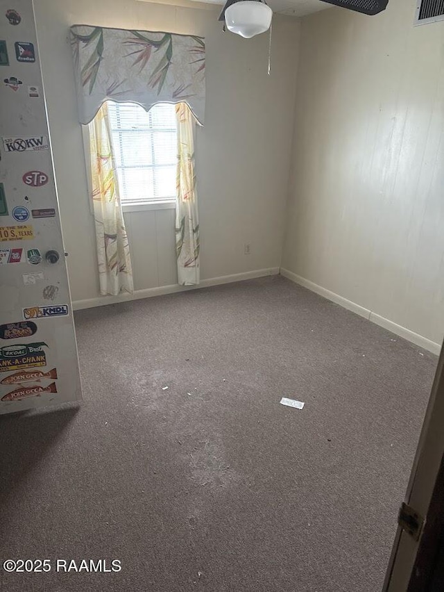 carpeted spare room with a ceiling fan, baseboards, and visible vents