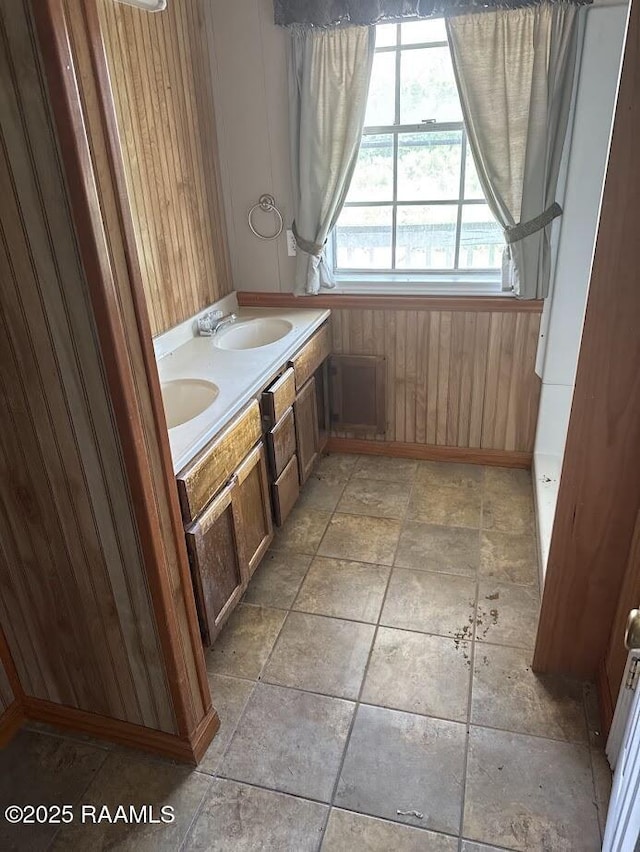 bathroom featuring wooden walls, stone finish flooring, and a sink