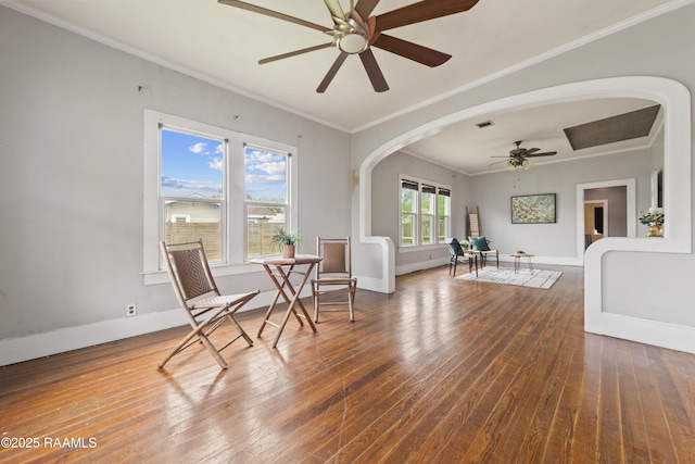sitting room featuring baseboards, wood-type flooring, crown molding, and a ceiling fan