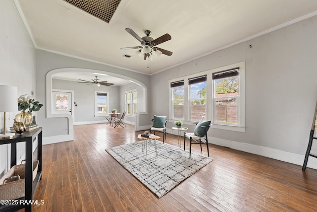 sitting room with crown molding, hardwood / wood-style flooring, a ceiling fan, baseboards, and arched walkways
