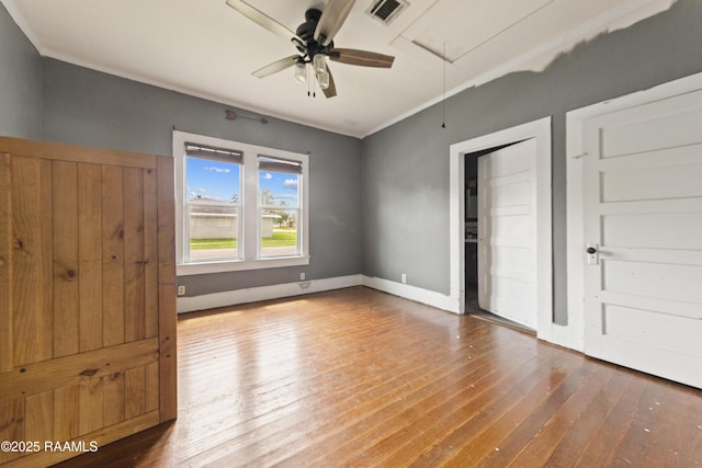 unfurnished bedroom with hardwood / wood-style floors, baseboards, attic access, and visible vents
