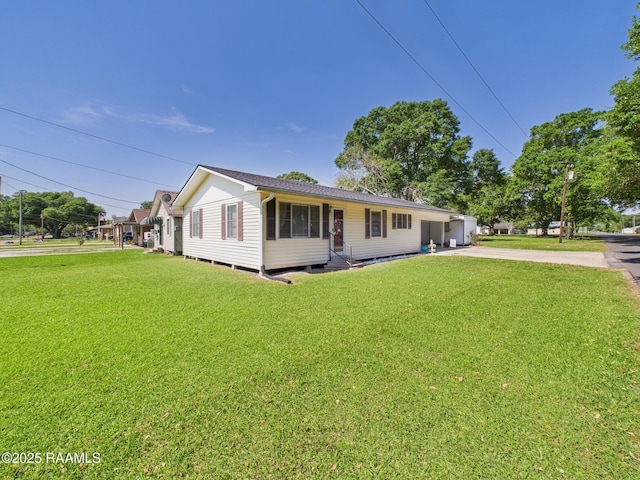 view of front of home featuring a shingled roof, a front yard, and concrete driveway