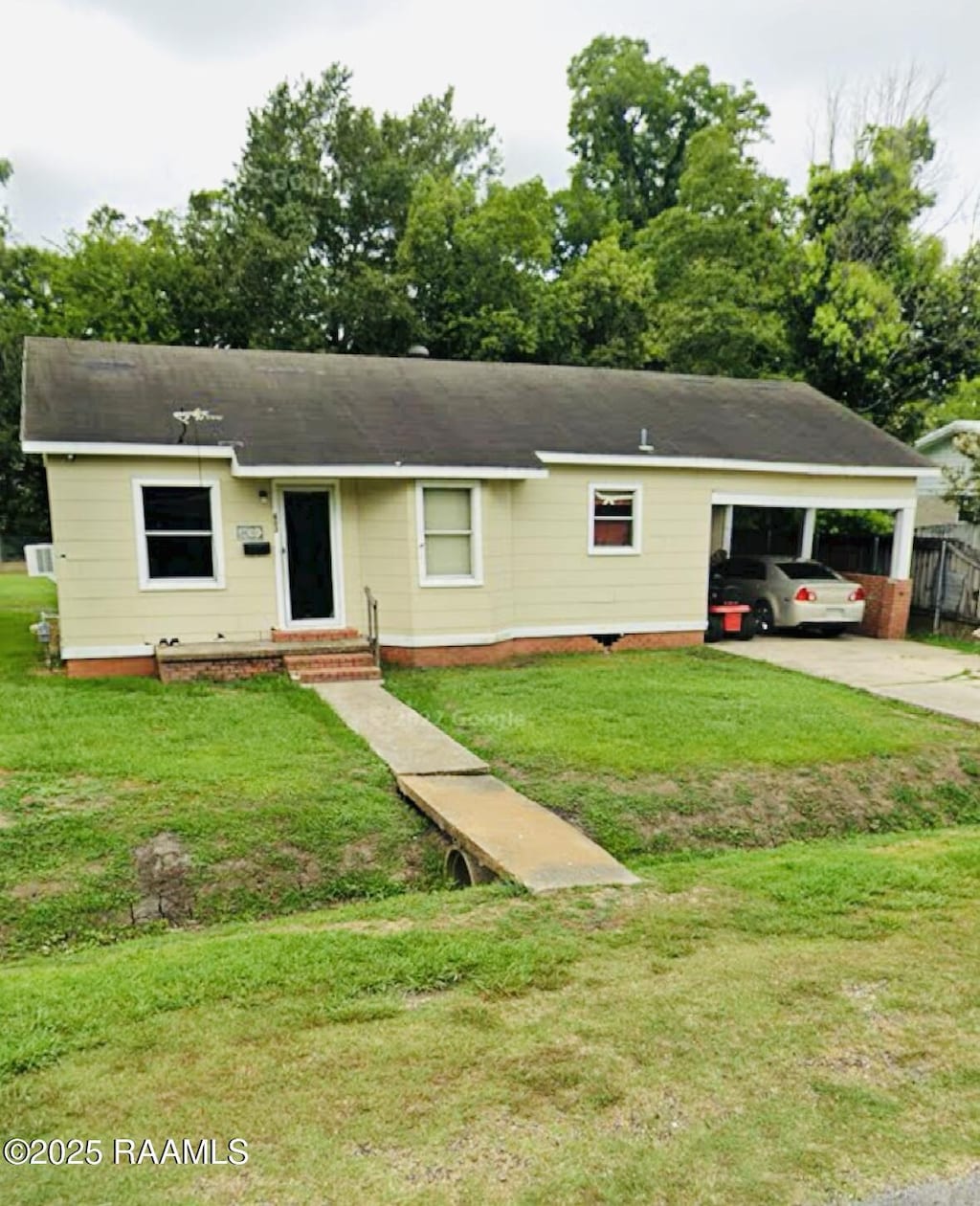 ranch-style home with a front yard, an attached carport, and driveway