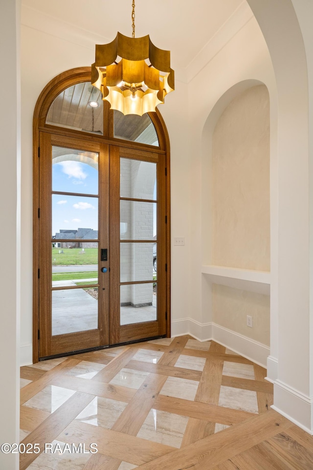 207 Sunset Palm Ct, Youngsville, LA 70592 - foyer entrance featuring a chandelier, french doors, arched walkways, and crown molding