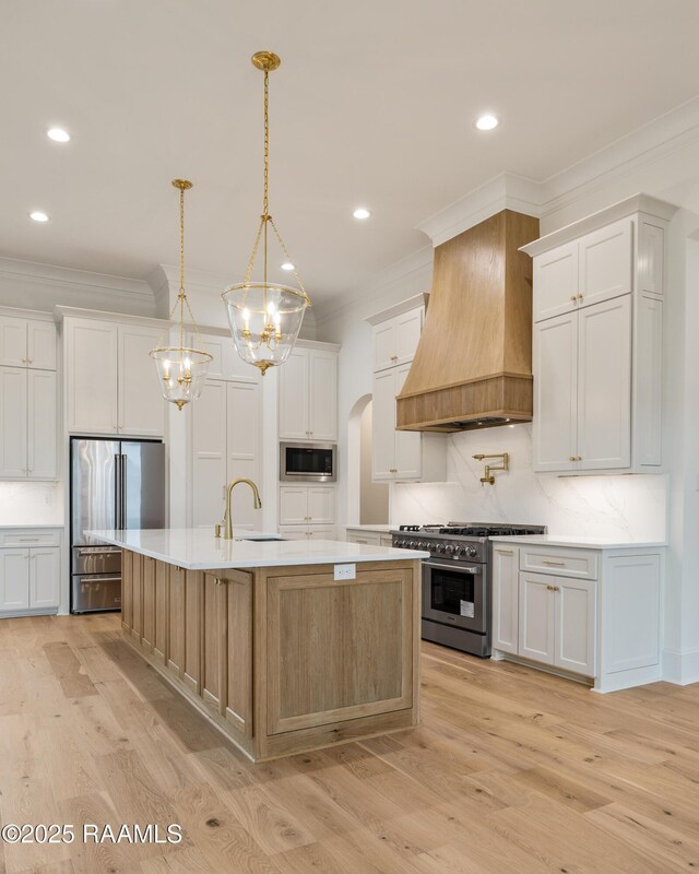 207 Sunset Palm Ct, Youngsville, LA 70592 - kitchen featuring high end appliances, custom range hood, crown molding, light wood finished floors, and light countertops