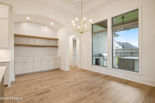 207 Sunset Palm Ct, Youngsville, LA 70592 - unfurnished dining area featuring arched walkways, light wood-style floors, a chandelier, and crown molding
