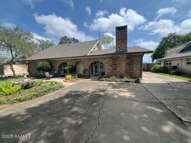 view of front of house with brick siding, a chimney, and concrete driveway