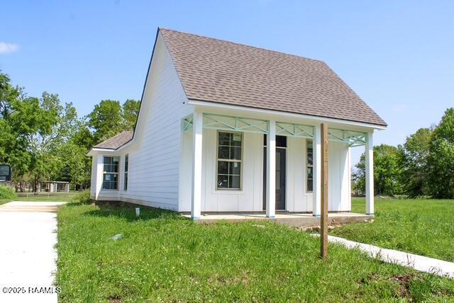 view of front of property featuring a front yard, board and batten siding, and roof with shingles