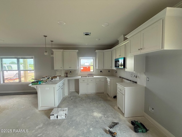 9923 Jimmie Rd, Kaplan, LA 70548 - kitchen featuring a peninsula, stainless steel microwave, plenty of natural light, ornamental molding, and white cabinets