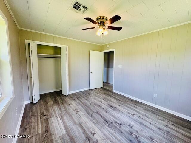 336 Harmon Ln, Opelousas, LA 70570 - unfurnished bedroom featuring ornamental molding, wood finished floors, a closet, a ceiling fan, and baseboards