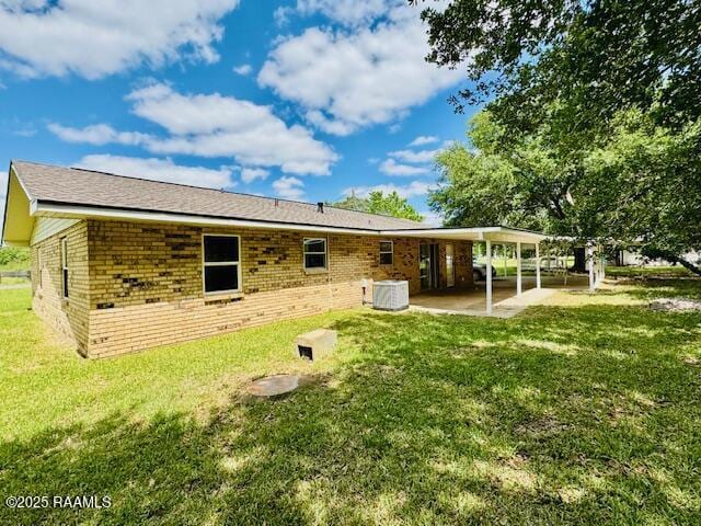 336 Harmon Ln, Opelousas, LA 70570 - back of property featuring a patio, brick siding, central AC, and a yard