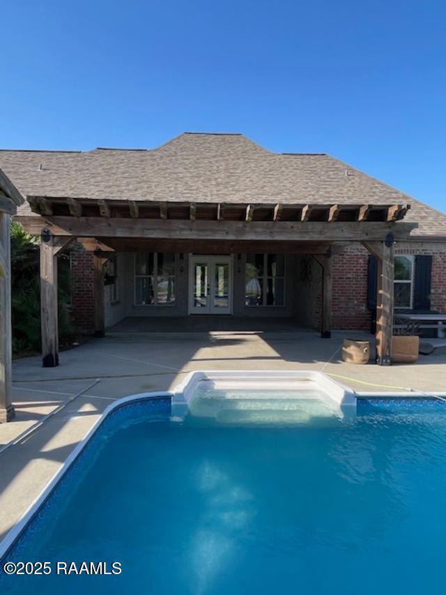 swimming pool with a patio area and french doors