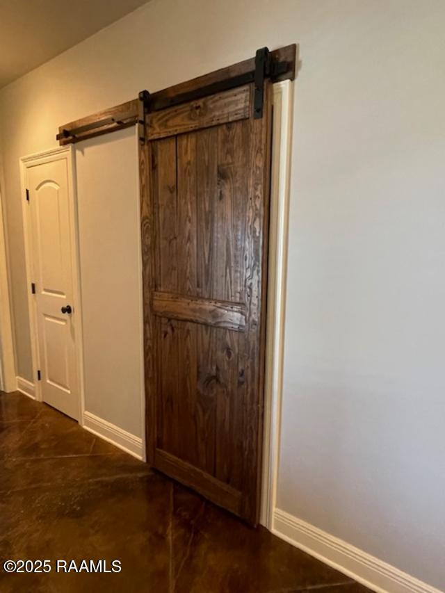 detailed view of a barn door, baseboards, and finished concrete flooring