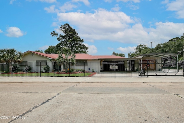 view of front facade with metal roof, driveway, and a fenced front yard