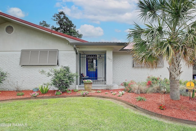 doorway to property featuring a yard and brick siding