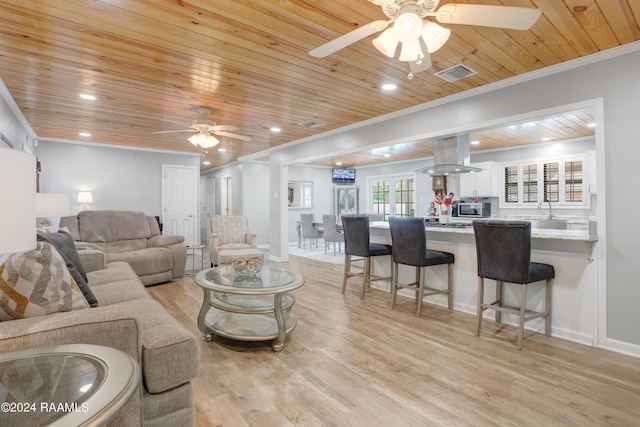 living area featuring light wood-style flooring, visible vents, ceiling fan, and crown molding