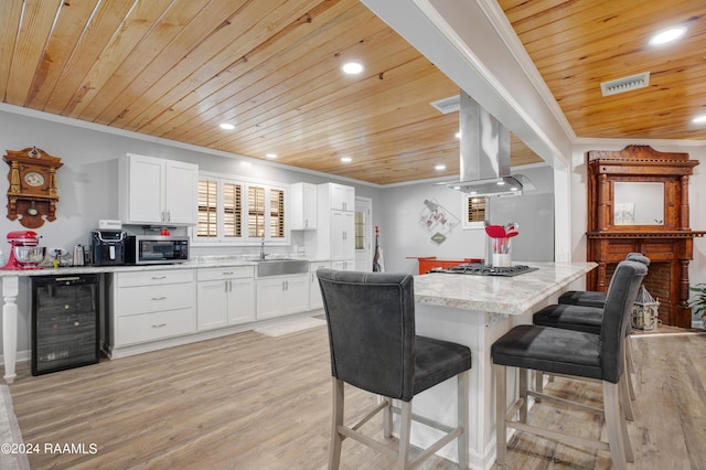 kitchen with ornamental molding, wood ceiling, appliances with stainless steel finishes, island exhaust hood, and beverage cooler