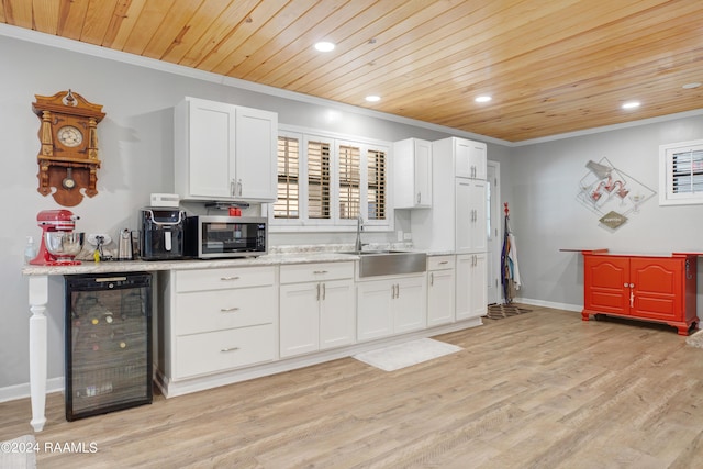 kitchen featuring crown molding, wood ceiling, stainless steel microwave, a sink, and wine cooler
