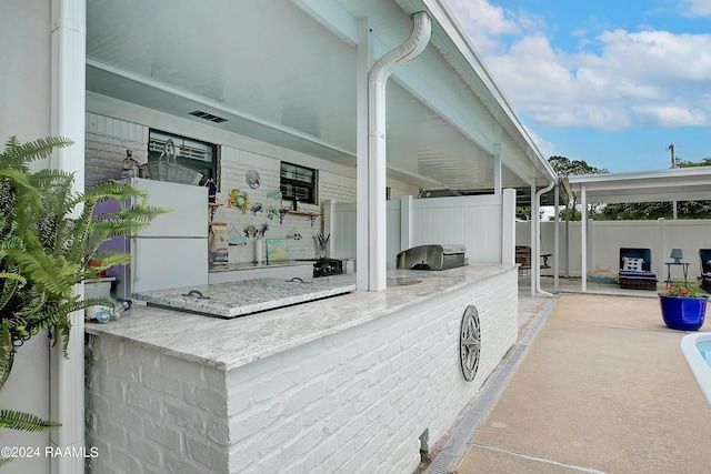 view of patio / terrace featuring an outdoor kitchen, fence, and visible vents