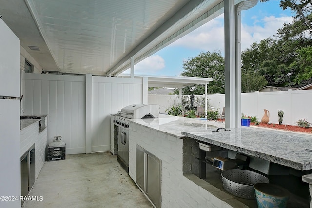 view of patio / terrace with exterior kitchen, a fenced backyard, and a grill