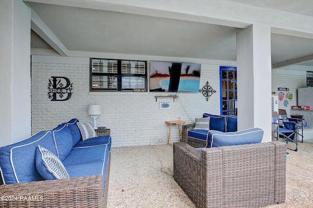 living room featuring beam ceiling, carpet, and brick wall