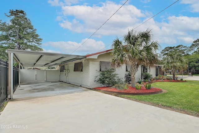 view of front of property with a front yard, fence, brick siding, driveway, and an attached carport