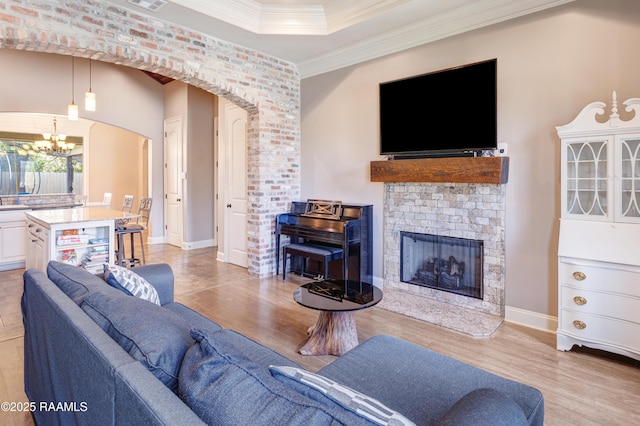 living area featuring crown molding, arched walkways, light wood finished floors, a notable chandelier, and visible vents