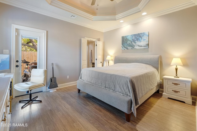 bedroom with light wood-style flooring, baseboards, visible vents, crown molding, and a raised ceiling