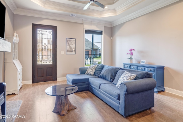 living area featuring visible vents, baseboards, light wood-style floors, ceiling fan, and crown molding