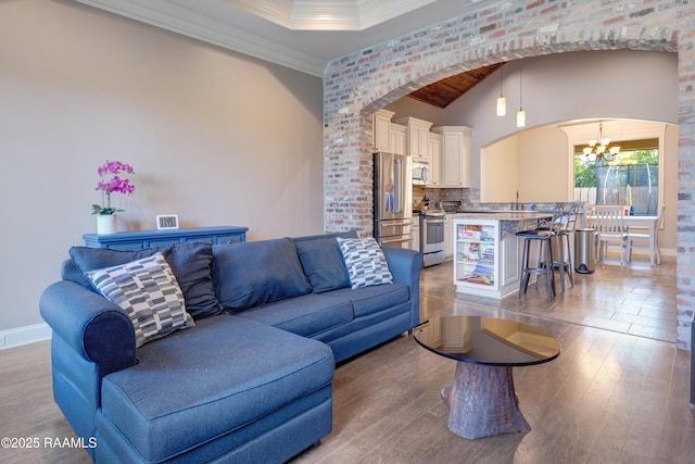 living room featuring baseboards, wood finished floors, arched walkways, and a chandelier