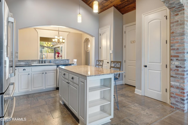 kitchen featuring stone tile floors, open shelves, a sink, freestanding refrigerator, and wood ceiling