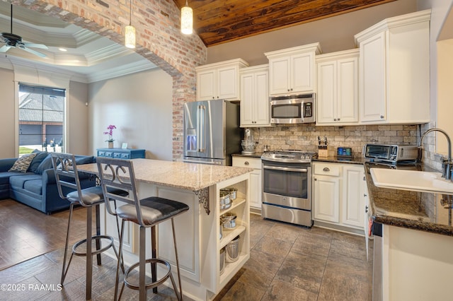 kitchen with stainless steel appliances, a center island, a sink, backsplash, and a ceiling fan