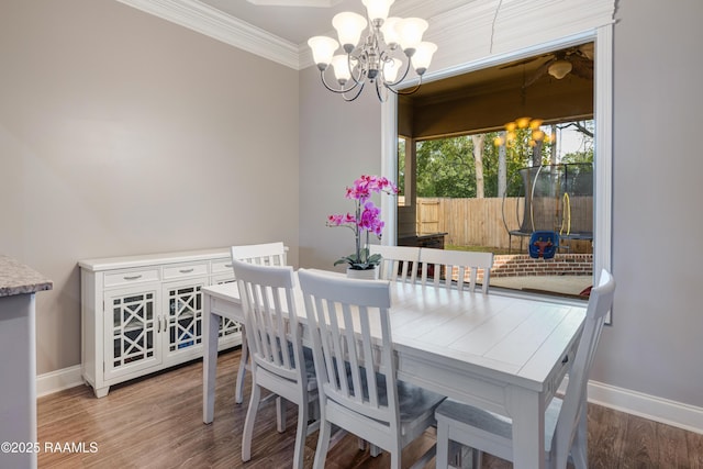 dining area featuring baseboards, a notable chandelier, wood finished floors, and crown molding